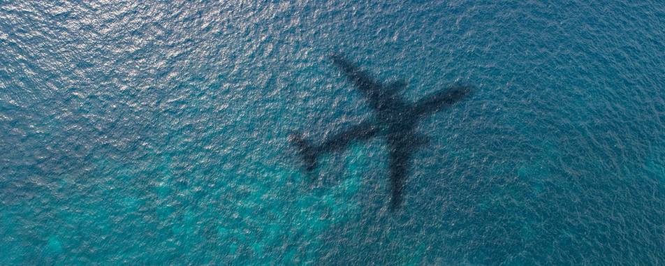 Sombra do avião voando sobre a água azul